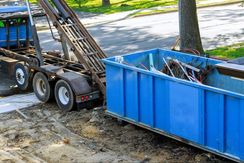 blue junk removal container being hooked to truck